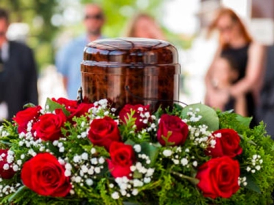 Urne funéraire brune entourée de fleurs rouges pendant une cérémonie d’obsèques