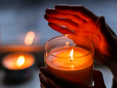 Mains entourant une bougie allumée, symbole de recueillement et de prière