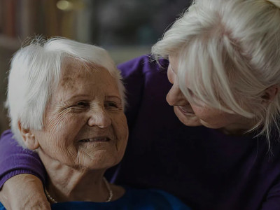 Femme âgée souriante soutenue par une accompagnante dans un cadre de soins palliatifs