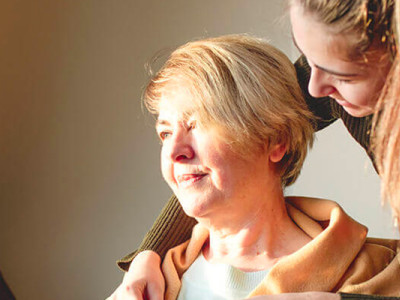 Femme âgée souriante accompagnée d’une jeune femme à son domicile, accompagnement à domicile Visitatio Voisins et Soins