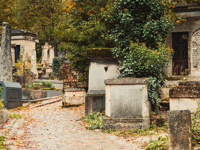 Sentier de cimetière ancien serpentant entre tombes et végétation d’automne