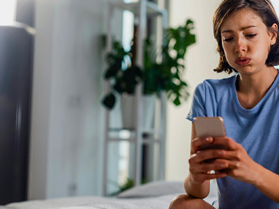 Jeune femme submergée face à son téléphone, illustrant la difficulté des démarches après un décès