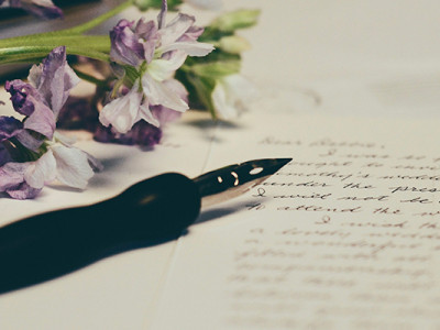 Rédaction manuscrite d’un testament avec un stylo plume et des fleurs en arrière-plan