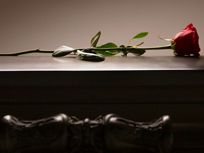 Cercueil en bois sombre avec une rose rouge, symbole de la mise en bière lors des obsèques
