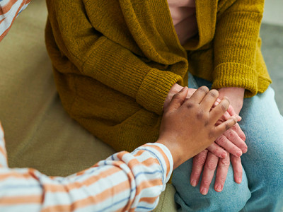 Deux femmes se tenant les mains dans un geste de soutien lors d’un accompagnement dans le deuil par une assistante sociale
