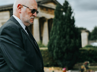 Employé de pompes funèbres en costume noir lors d’une cérémonie d’obsèques dans un cimetière