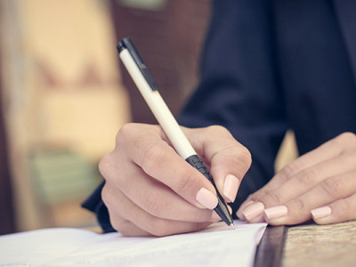Main qui signe un contrat obsèques pour anticiper l’organisation des funérailles